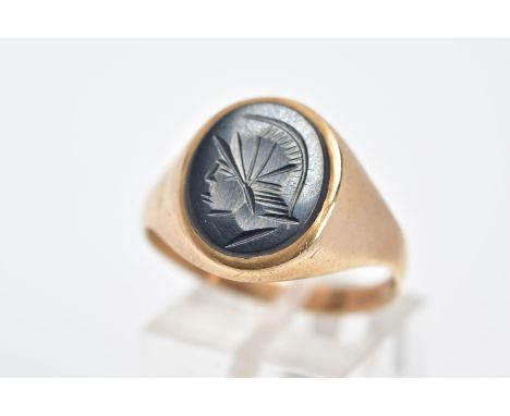 A 9CT GOLD GENTS HEMATITE INTAGLIO SIGNET RING, of an oval form depicting a Roman soldier, plain polished shoulders, ring siz