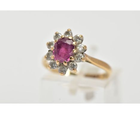 A 9CT GOLD RUBY AND DIAMOND CLUSTER RING, centring on an oval cut ruby, within a claw set, round brilliant cut diamond surrou