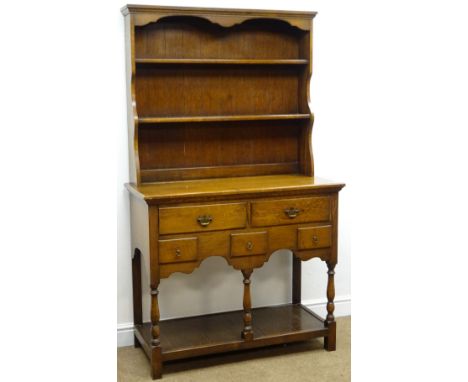 Early 20th century medium oak dresser, projecting cornice above two shelf plate rack, two long and three short drawers, turne