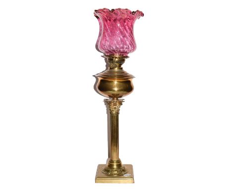 A Victorian brass Corinthian Column Oil lamp with cranberry glass shade, overall height including funnel 77cm