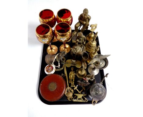A tray containing assorted brass ornaments, hand bells, vintage tape measure, ruby and gilt wine goblets 