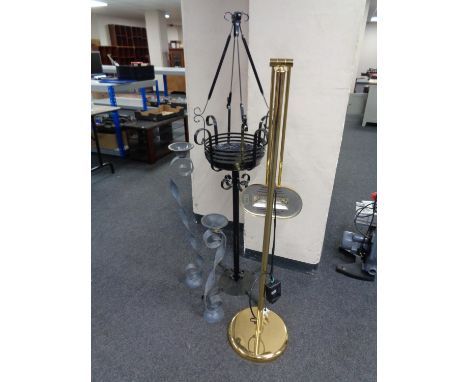 A wrought iron plant stand together with two metal candle holders and brass floor standing lamp 