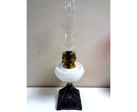 An English Search oil lamp on cast iron base with opaque reservoir and chimney 