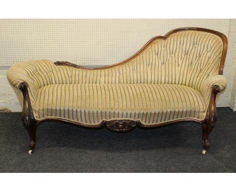 A Victorian walnut chaise longue with raised swept back, scroll ends, raised on cabriole forelegs, knuckle feet and ceramic c