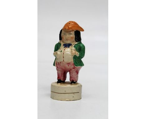 An early 19th century creamware sander fashioned as a toper wearing a tricorn hat, with ale jug and pipe before him, 15.5cm