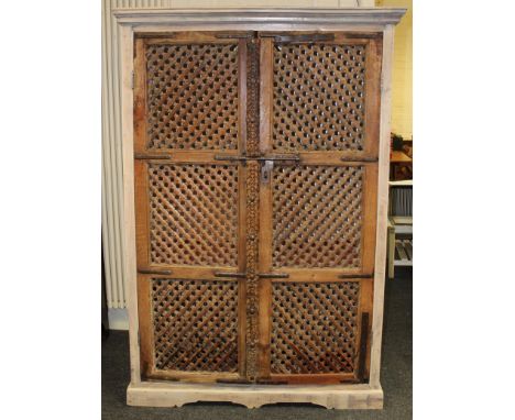 A painted hardwood cupboard, having a pair of Asian influence slatted metal bound panel doors, enclosing two shelves and wine