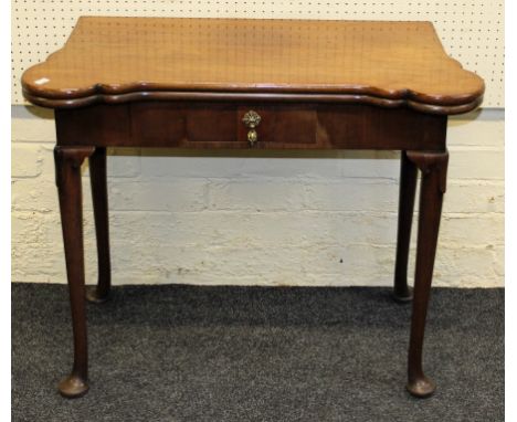 A George III mahogany games table, the lobed rectangular folding top baize lined and fitted with oval wells and dished coaste