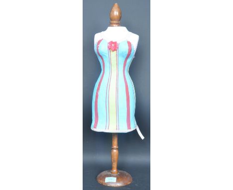 A vintage 20th century haberdashery style tailors dummy - table top mannequin dressed in a striped dress and raised on wooden