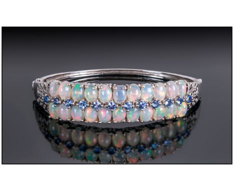 Opal and Tanzanite Bangle, comprising two rows of oval cut cabochon opals highlighted with a row of round cut tanzanites, spa