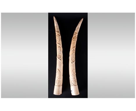 An Antique Pair Of Carved Ivory Tusks, Decorated with raised images of wild animals. Weight 1304grams. Each 20'' in length.