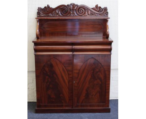 An early Victorian figural mahogany chiffonier, the scroll carved back over a pair of flush frieze drawers and a pair of pane