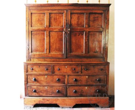 A George III Welsh oak housekeepers cupboard, with two fielded cupboard doors enclosing shelves above an arrangement of seven