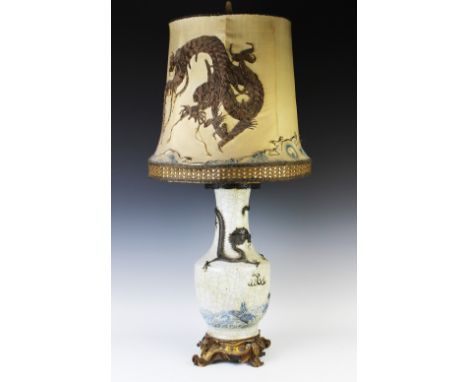 A Chinese crackle glaze lamp, moulded with a dragon and a carp, with an embroidered shade, with gilt metal Rococo style mount