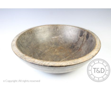 A 19th century vernacular turned sycamore dairy bowl of large proportions, old rivet repair, 56cm diameter (at fault) with a 