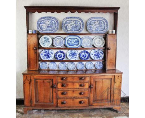 A George III Welsh inlaid oak high back dresser, possibly Montgommery, the serpentine cornice above three open shelves, cupbo