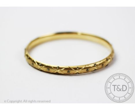 A yellow gold bangle, the hinged bangle stamped '14k', with facteted decoration throughout, gross weight 7.1gms 