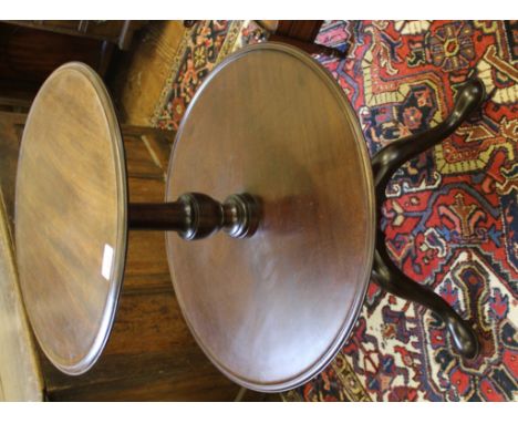 An early 19th century two-tier circular dumb waiter with shaped platforms, raised on a baluster-shaped central column and tri
