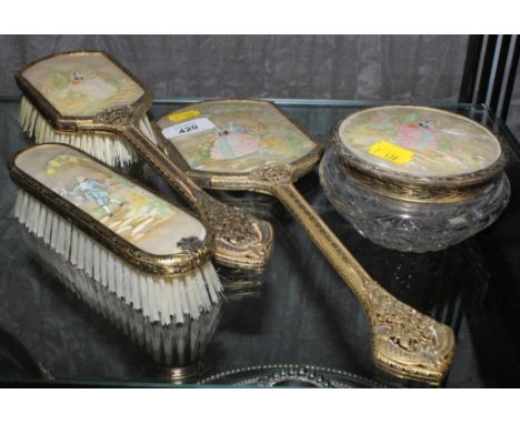 An early 20th century lady's vanity set with brass frames and mother of pearl depictions comprising hair brush, mirror, cloth