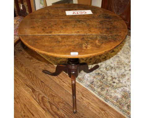 A Georgian elm wood circular flip-top occasional table (flip top fixed), raised on a stained oak baluster shaped central colu