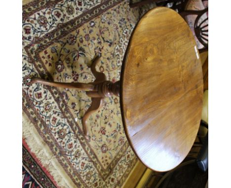 A George III elm provincial circular flip-top table with turned central column on tripod base, 70H x 77cmD