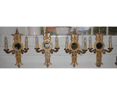 A set of four 19th century mirror backed brass wall sconces with intricate carving and fret work, fitted for electricity, eac