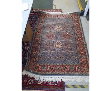 Ikaros machine woven woollen rug decorated with a floral pattern on a light blue and terracotta ground with multiguard border