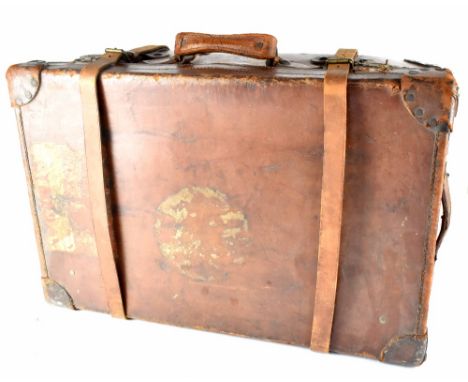 An early 20th century brown leather travel trunk, initialled FWS and ACCRA, and bearing the remnants of various travel labels