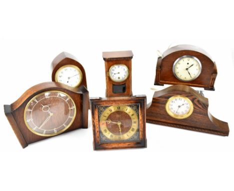 Six early/mid-20th century mantel clocks to include an oak example in the form of a longcase clock, a mahogany inlaid example