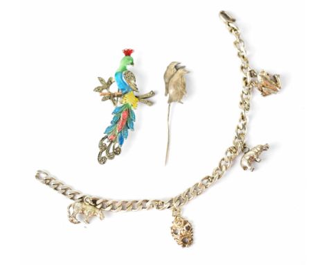 A sterling silver charm bracelet with four charms, a vintage bird-form enamel brooch and a sterling silver penguin-form stick