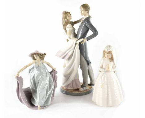 A large Lladró figure of a newlywed couple dancing, height 38cm, a Lladró lady with large bonnet and flowing robes and a Nao 