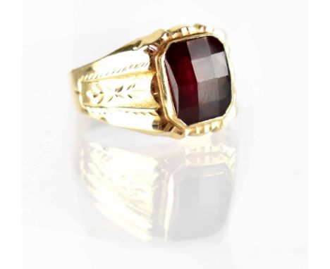 A gentlemen's yellow metal dress ring set with facet-cut ruby within a band with engraved foliate shoulders, size Y, approx 5