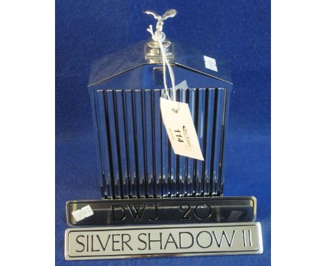 A Rolls Royce radiator grill shaped decanter or flask. Together with a chrome badge from a Silver Shadow. Similar chromed fac