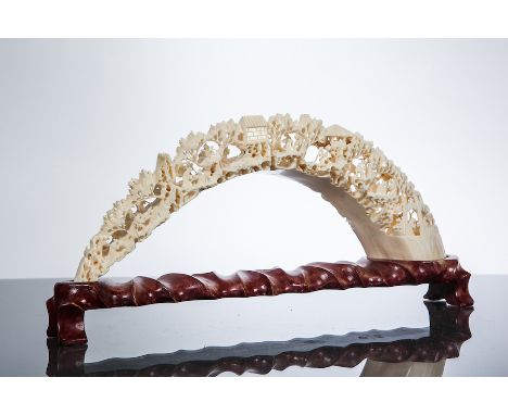 CHINESE IVORY CARVING 
possibly hippopotamus tusk, of bridged form and showing figures and architectural features in a landsc