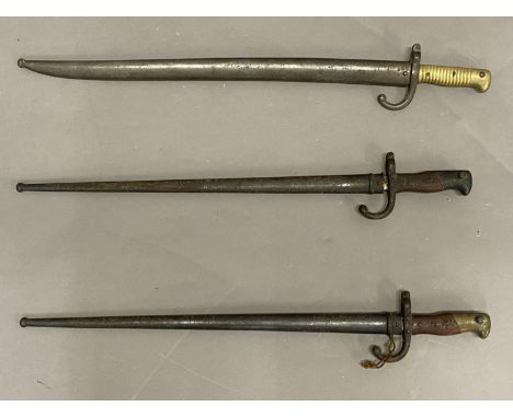 THREE SIMILAR FRENCH SWORD BAYONETS AND SCABBARDS. A French bayonet, with a 52.5cm pointed blade, the back marked St Etienne 