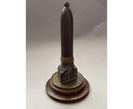 A FIRST WORLD WAR NAVAL SOUVENIR. A desk ornament with central bullet shaped upright on a circular base engraved 'A PIECE Of 