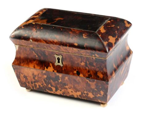 An early 19th Century tortoiseshell tea caddy, of sarcophagus form, with brass stringing and escutcheon, opening to reveal a 