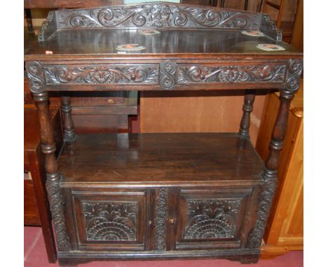 A circa 1900 low relief carved oak three-quarter gallery backed two drawer buffet, having twin lower cupboard doors
