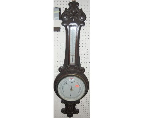 An early 20th century carved oak two dial aneroid wheel barometer
