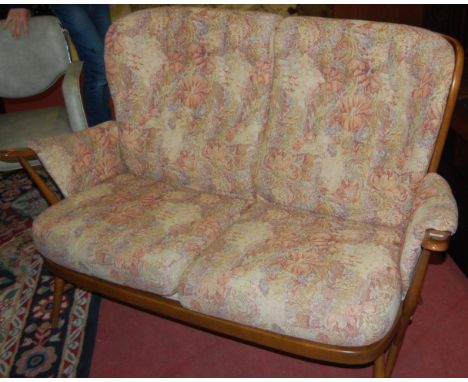 An Ercol mid-elm three piece lounge suite comprising; double sofa and a pair of armchairs, each with floral upholstered butto