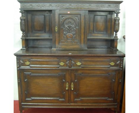 An early 20th century low relief carved and panelled oak buffet side cupboard