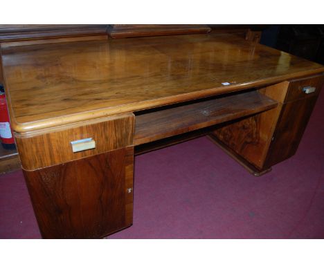 An Art Deco figured walnut twin pedestal writing desk, having four quarter veneered top over two short drawers to conforming 