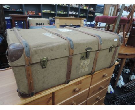 A vintage canvas bound cabin trunk having railway labels etc