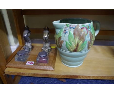 A dolphin form desk stand; together with a Clarice Cliff 'Autumn Leaves' jug, (a.f.).