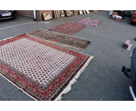 A large rug having repeated field; together with a Persian rug fragment, an Afghan rug having red ground, and one other, larg