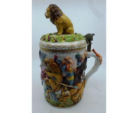 An early 20th Naples porcelain tankard relief moulded with a lion hunt, the hinged cover with lion finial, 27cm high