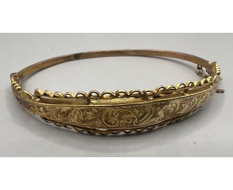 A 9ct gold hinged hollow bangle with wire and engraving decoration. Hallmarked Birmingham 1915. As found due to dents. Approx