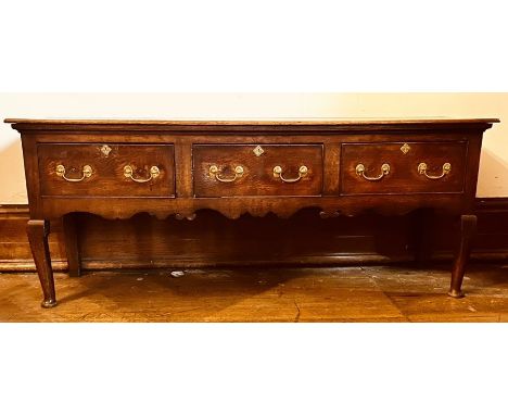 A George II oak dresser base, single plank top in rectangular form, above three frieze drawers with later brass handles escut