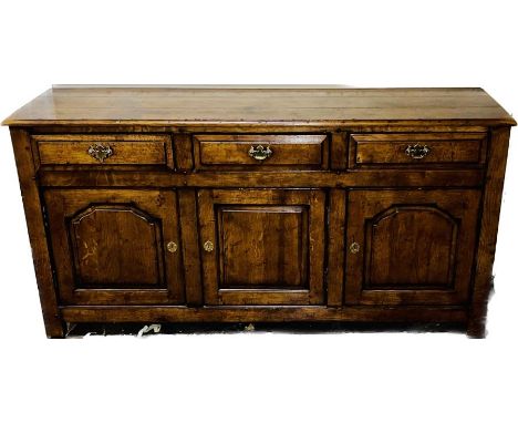 A George III and later oak dresser base sideboard, slight overhanging top above three frieze drawers with later batwing brass