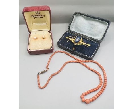 A blue Wedgewood Jasperware brooch, with a graduated coral bead necklace and pearl earrings. The Wedgewood piece depicts the 
