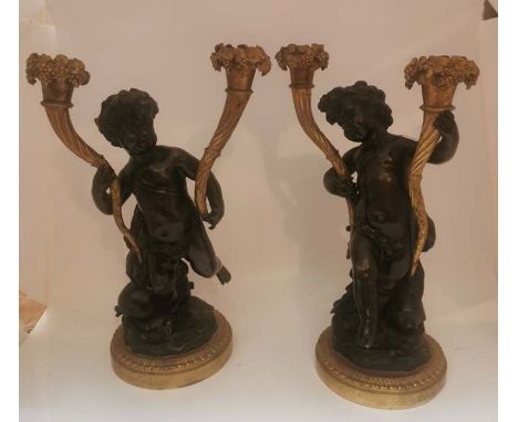 A pair of early 19th century bronze and gilt candle holders in the form of young boys swinging their legs, with grapes decora